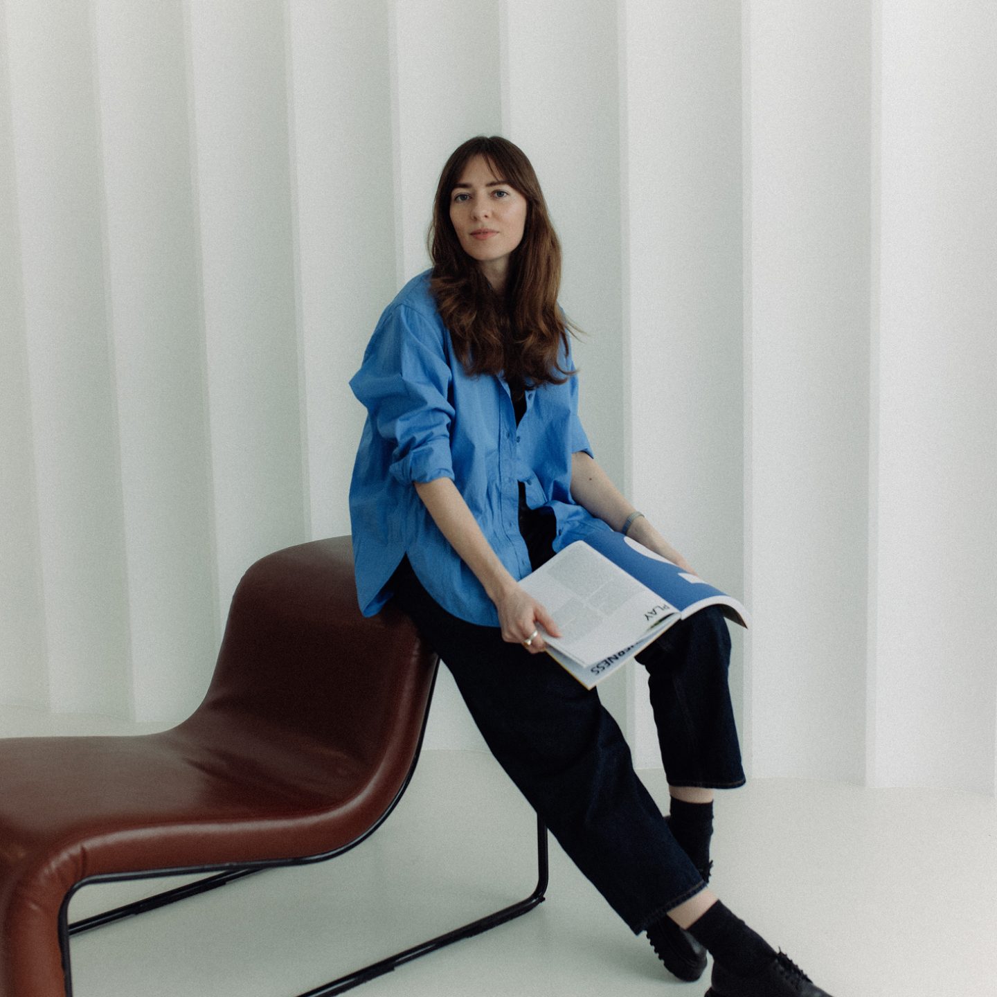Ilona sitting on a leather chair with a magazine