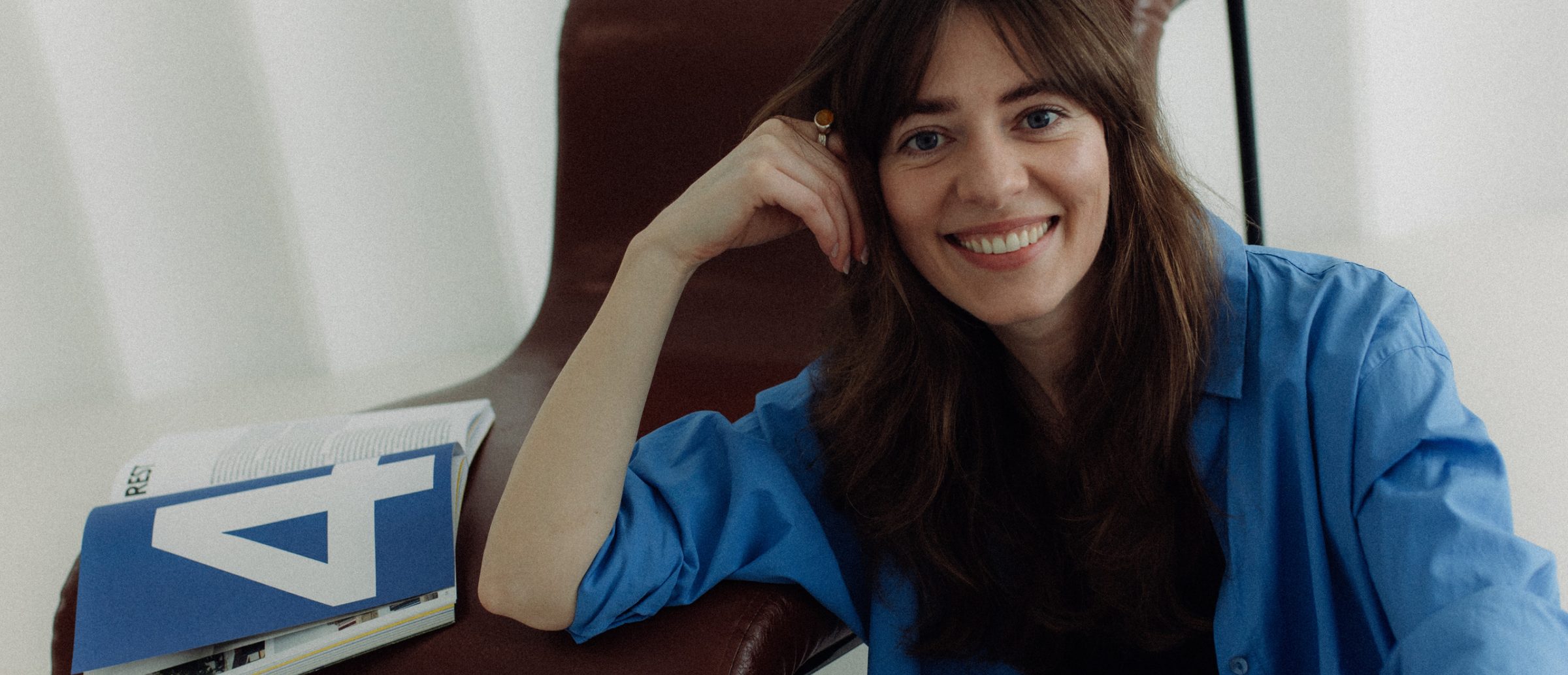 Ilona, founder of Nowadays People, smiling in a leather chair